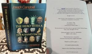 Book cover of 'The Hero with a Thousand Faces' by Joseph Campbell with various masks and statues.